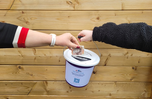 A £10 note being put into a Fifth Trust collection bucket
